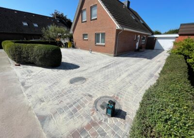 Steinpflasterung vor einem roten Backsteinhaus, professionell von Th. Andresen Galabau verlegt