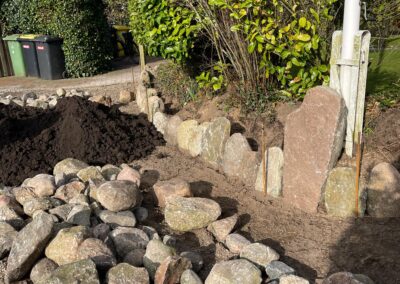 Friesenwall bei Gartenrenovierung im Garten mit Büschen und Erdhaufen
