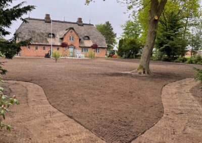 Garten-Design mit individuell angelegtem Weg und Baum vor traditionell reetgedecktem Friesenhaus
