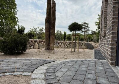 gestalteter Gartenweg mit Natursteinpflaster und Sandflächen, professionell angelegte Garten- und Landschaftsgestaltung